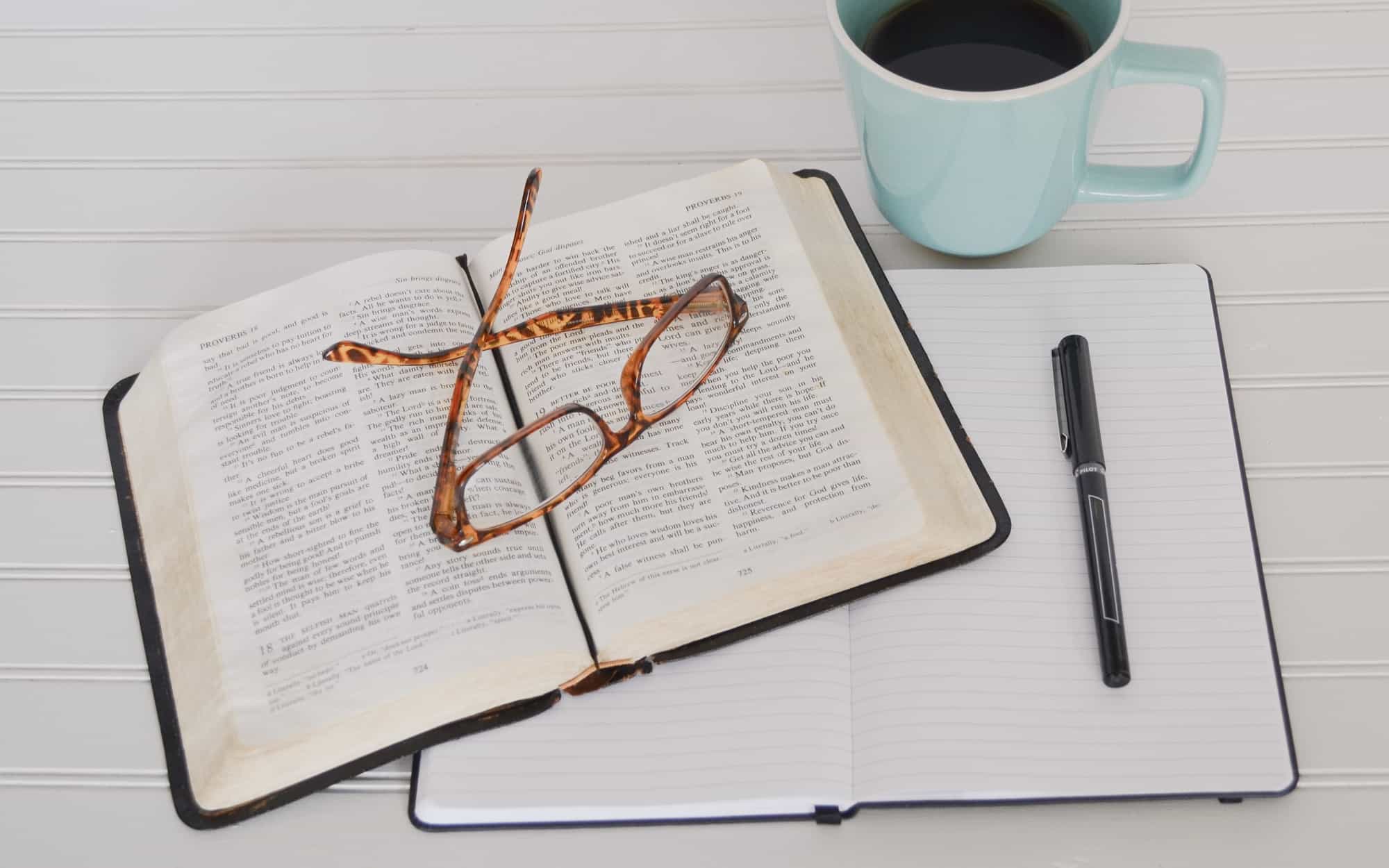 Bible, glasses, notebook, coffee on a table